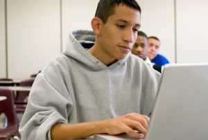 Teenager working on laptop in classroom